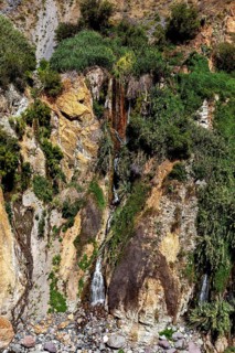 Waterfall flowing among green shrubs and rocks, The landscape of the Colca Canyon in the Andes of