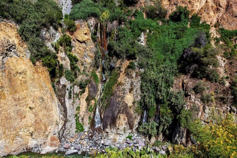 Small waterfall flowing over green and rocky cliffs, the landscape of the Colca Canyon in the Andes