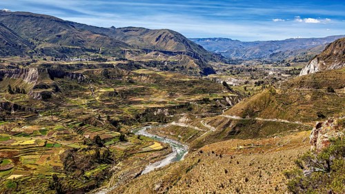 Extensive terraced valleys with towering mountains and a river, the landscape of the Colca Canyon