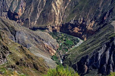 Dramatic gorge with lush greenery in the valley floor surrounded by steep cliffs and hiking trails,