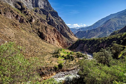 Wide valley with green vegetation and river, surrounded by imposing mountains, the landscape of the