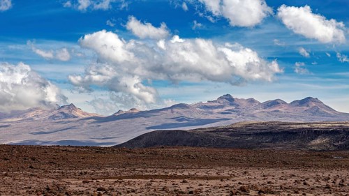 Barren landscape with mountains in the background and scattered clouds in the sky, The highlands of