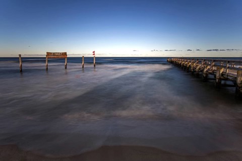 Wooden sign in the sea with inscription Zingst and wooden walkway, long exposure, evening light,