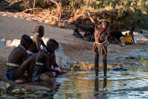 Himba child washing with water on a river, traditional Himba, Kaokoveld, Kunene, Namibia