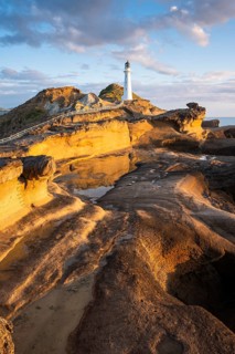 Castlepoint lighthouse on a rock, sea, sunrise. Castlepoint, Wairarapa Coast, Wellington Region,