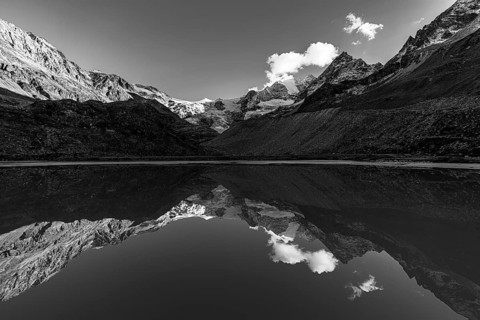 The Moiry glacier and mountain peaks are reflected in Lac de Chateaupre, black and white photo, Val