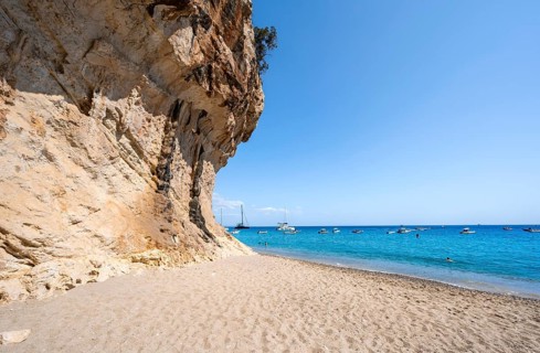 Sandy beach beach and steep cliffs at Cala Luna, Golfo di Orosei, Baunei, Sardinia, Italy