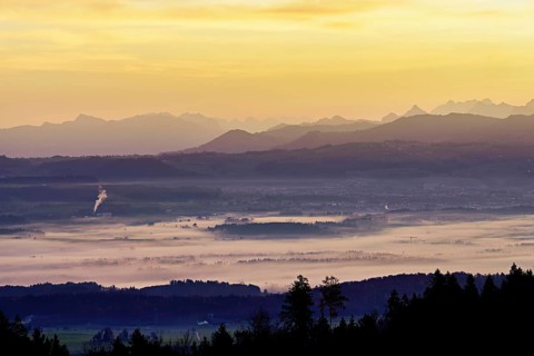 View from Horben of the Reuss Valley covered in fog, behind it the Glarus Alps in the light of the