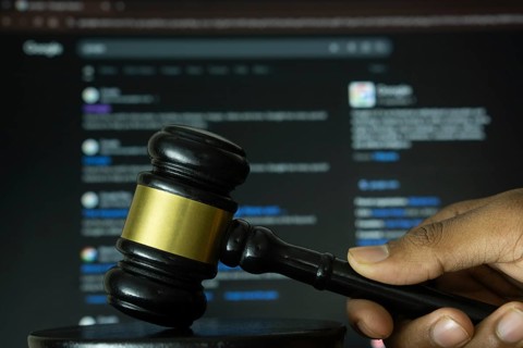 Dhaka, Bangladesh- 20 June 2025: A hand holds a gavel in front of a computer screen displaying