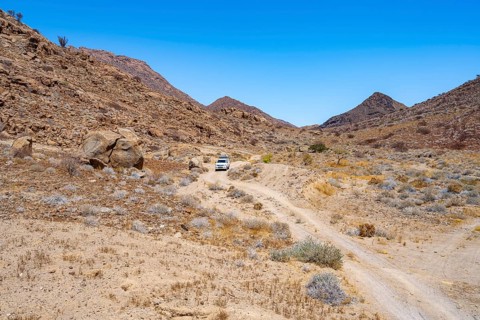 Toyota Hilux off-road vehicle on a sandy track, desert landscape with Brandberg, Erongo,