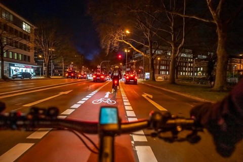 Cycling in the city, in the dark, in the evening, cycling on a bike lane, marked in red,