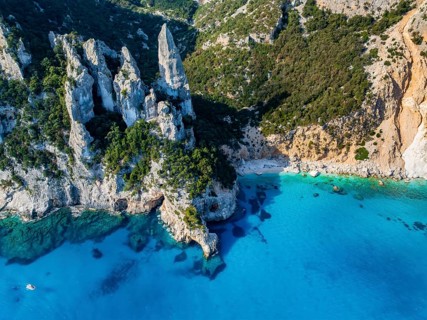 Picturesque rocky coast, cliffs with L'Aguglia pinnacle, blue sea and Cala Goloritzé beach, aerial