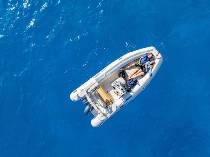 Young woman and young man lying in a motor boat on a blue sea, top-down, aerial view, Golfo di