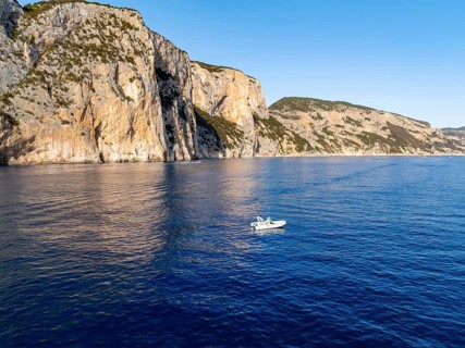 Motorboat off picturesque rocky coast ImmorgenLicht, cliffs, Golfo di Orosei, Baunei, Sardinia,
