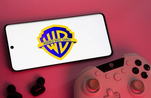 Dhaka, Bangladesh- 22 Mar 2025: Smartphone with Warner Bros. Games logo, game controller, and