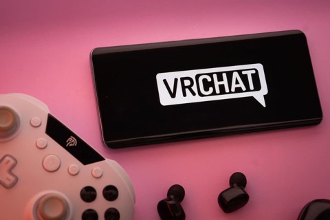 Dhaka, Bangladesh- 22 Mar 2025: Smartphone with VRChat logo, game controller, and earbuds on a pink