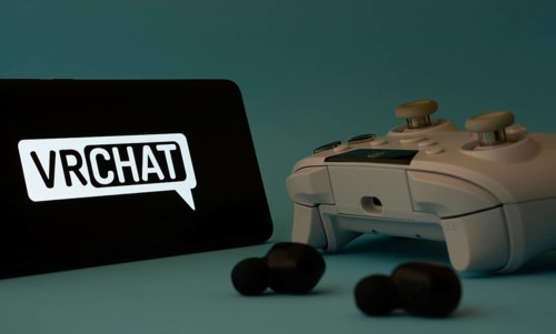 Dhaka, Bangladesh- 23 Mar 2025: A smartphone with a VRChat icon next to a controller and earbuds on