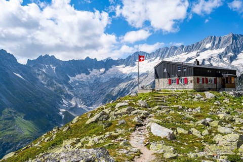 Mountain hut Bergseehütte with Swiss flag in picturesque mountain landscape, view of Damma Glacier