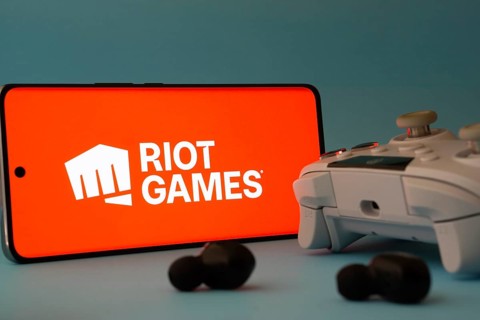 Dhaka, Bangladesh- 23 Mar 2025: A smartphone with a Riot games icon next to a controller and