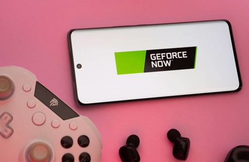 Dhaka, Bangladesh- 22 Mar 2025: Smartphone with Geforce Now logo, game controller, and earbuds on a