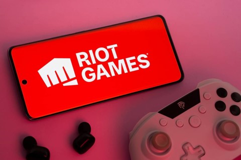 Dhaka, Bangladesh- 22 Mar 2025: Smartphone with Riot Games logo, game controller, and earbuds on a