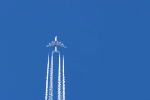 Airbus A380 jet passenger aircraft of Emirates airlines flying in a blue sky with contrails or