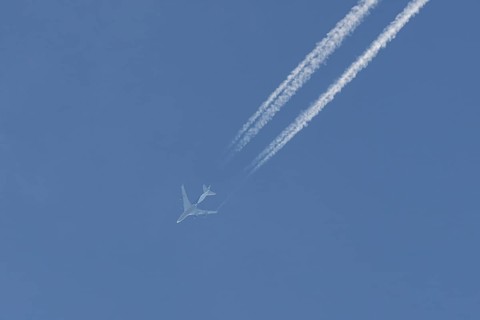 Boeing 747 jumbo jet cargo aircraft flying in a blue sky with contrails or vapour trails behind,