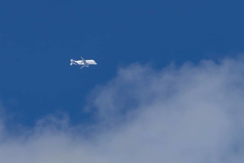 Airbus A330-743L Beluga XL cargo jet aircraft flying in a blue sky with white clouds, England,