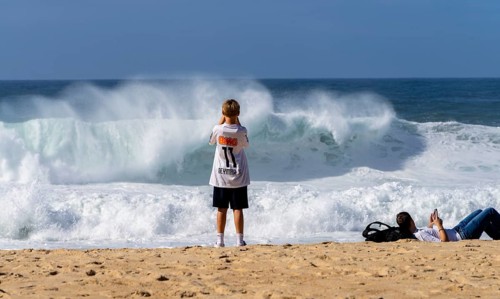 Tourists watch the waves of the Atlantic on the rocky plateau of Sito, also known as Forte São