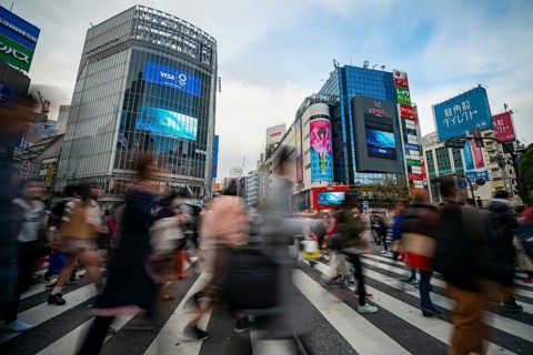 Crowd crossing zebra crossing on a large intersection, motion blur, back modern houses with