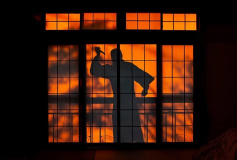 Shadow of a man, burglar with knife, assassin, ninja, on the balcony behind sliding shoji doors in