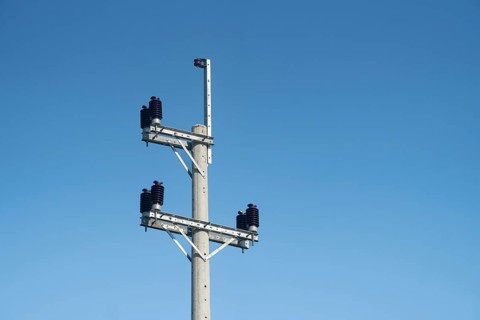 An electric pole with insulators and wires set against a clear blue sky on a bright day