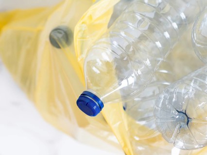 Plastic bottles inside a yellow trash bag awaiting recycling, promoting environmental