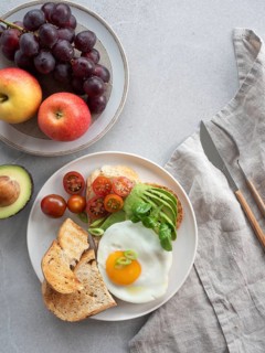 Enjoying a nutritious and delicious breakfast with whole wheat toast topped with avocado, a fried