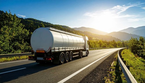 Petrol cargo truck lorry tanker driving on highway hauling oil products at sunrise, wide hilly