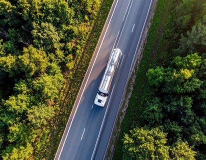 Petrol cargo truck lorry tanker driving on highway hauling oil products at sunrise, wide hilly