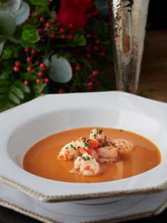 Creamy shrimp bisque soup with prawns, garnished with chives, on a white plate