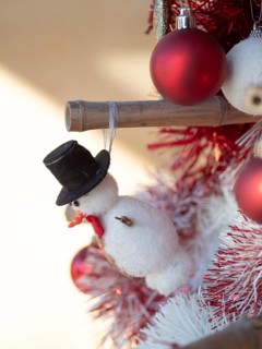 Festive snowman ornament with top hat decorating a cheerful christmas tree