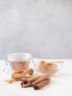 Cinnamon sticks and ground powder displayed on a white surface, ready for use