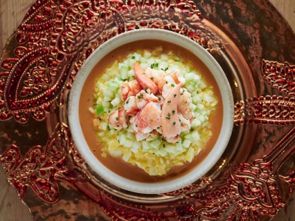 Gourmet lobster gazpacho with diced cucumber and chives, presented on an ornate platter