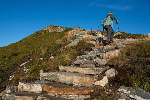 Woman with hiking poles walking up Rørsethornet stone stairs, with 3292 steps one of the longest