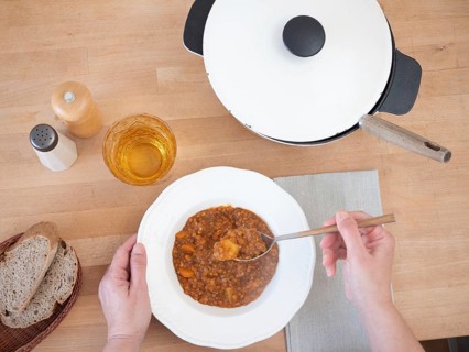 Woman eating a hearty lentil stew, served with whole wheat bread and a refreshing drink, creating a