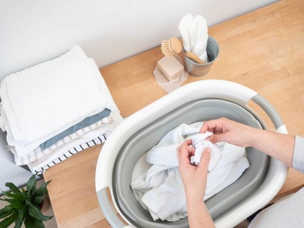 Woman inspecting clothes for stains before washing, preparing laundry in a sustainable way with