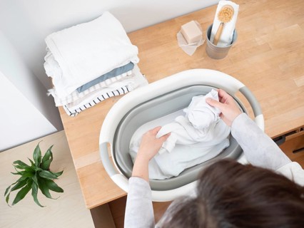 Housewife putting white clothes into a basin preparing laundry washing using natural soap bar and