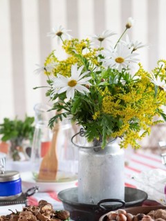White daisies and yellow goldenrod create a vibrant centerpiece in a rustic milk can, adding a