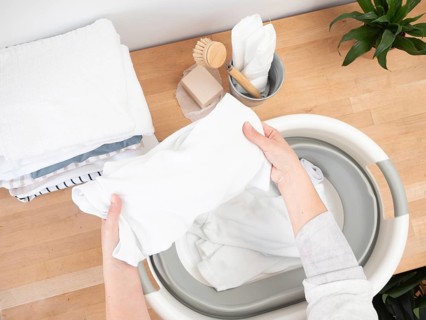 Housewife putting white clothes into basin, doing laundry chores at home