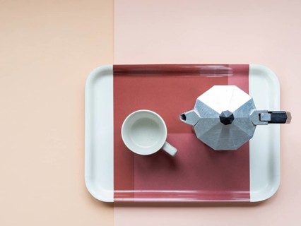 Overhead view of a moka pot and an empty coffee cup sitting on a serving tray, arranged on a