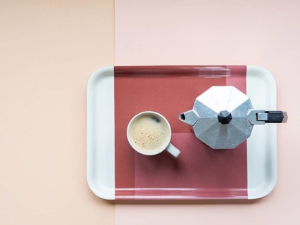 Coffee cup and moka pot sitting on a serving tray, minimalist flat lay on a pastel pink and beige