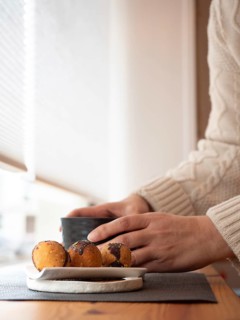 Woman enjoying a relaxing moment with coffee or tea and cookies in a cozy cafe by the window