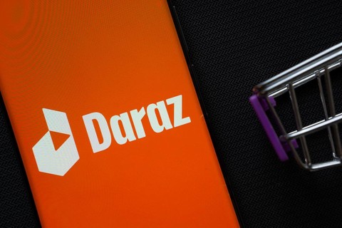 Dhaka, Bangladesh- 03 Oct 2025: A smartphone displaying the Daraz logo next to a miniature shopping